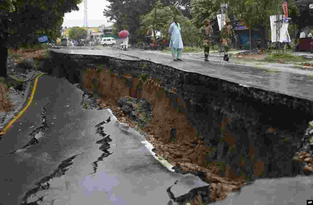 میرپور کے علاقے جاتلان میں پاکستان آرمی کے اہلکار ایک تباہ شدہ سڑک کے قریب سے گزر رہے ہیں۔&nbsp; &nbsp; &nbsp; 